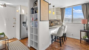 Eine moderne Küche mit integriertem Kühlschrank, einem Essbereich mit zwei Stühlen und einem Fenster mit Blick auf die Stadt.