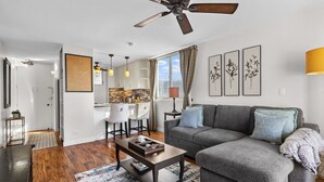 Ein modernes Wohnzimmer mit grauem Sofa, einem Holztisch und einem Deckenventilator.