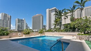 Ein Pool auf dem Dach mit Blick auf hohe Gebäude und Palmen.