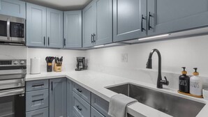 Cozinha moderna com armários cinza, eletrodomésticos de aço inoxidável e uma pia grande.