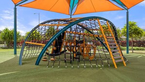 A playground with a net structure, slides, and a covered area.