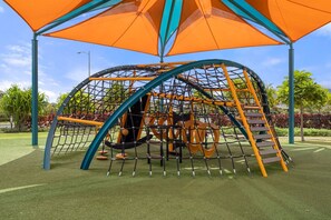 A playground with a net structure, slides, and a covered area. - Modern Island Living | Parking, AC, Fast WiFi, W/D (Ewa Beach)