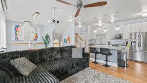 A modern kitchen with stainless steel appliances, a bar area, and a large black sectional sofa.