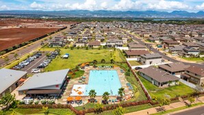 A residential area with a swimming pool surrounded by houses and a parking lot.