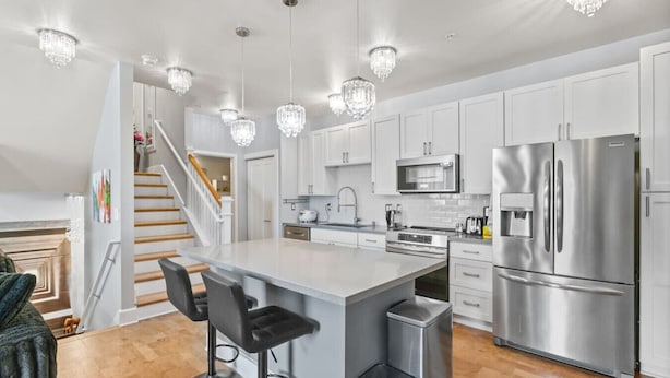 A modern kitchen with white cabinets, stainless steel appliances, and a central island with bar stools.