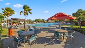 A poolside area with lounge chairs, a table, and a red umbrella.