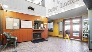 Eine Lobby mit einem Holzbüro, einer Sitzecke und einem großen Schild mit der Aufschrift Cedar Lodge.