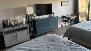 Ein Hotelzimmer mit Bett, Schreibtisch, Fernseher, einer Kaffeestation und einem Balkon mit Blick.