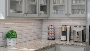 Cozinha com armários brancos, cafeteira e torradeira na bancada.