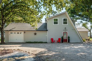 A single-story house with a garage, a red door, and two red chairs outside.