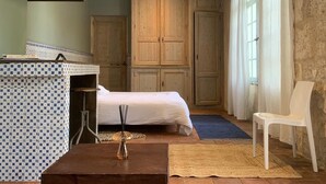 Une chambre à coucher comprenant un lit, une chaise, un bureau avec une lampe et des armoires en bois.