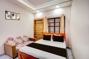 A bedroom with a bed, a sofa, and a window with curtains. - P1 Staycation (Pune)