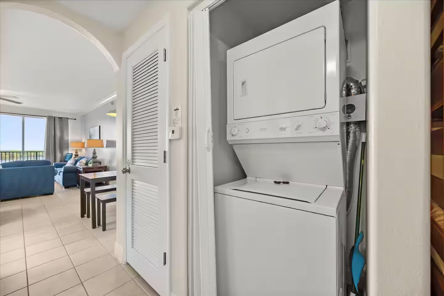 Een hotelkamer met een wasruimte, een eethoek met een tafel en stoelen, en een balkon met uitzicht.