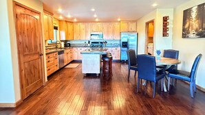 Una cocina amplia con armarios de madera, una isla central y un comedor con sillas.