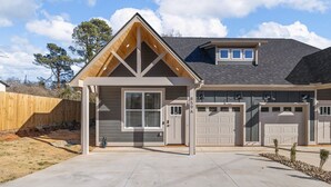 Une maison à deux étages avec un garage, une véranda et une pelouse bien entretenue.