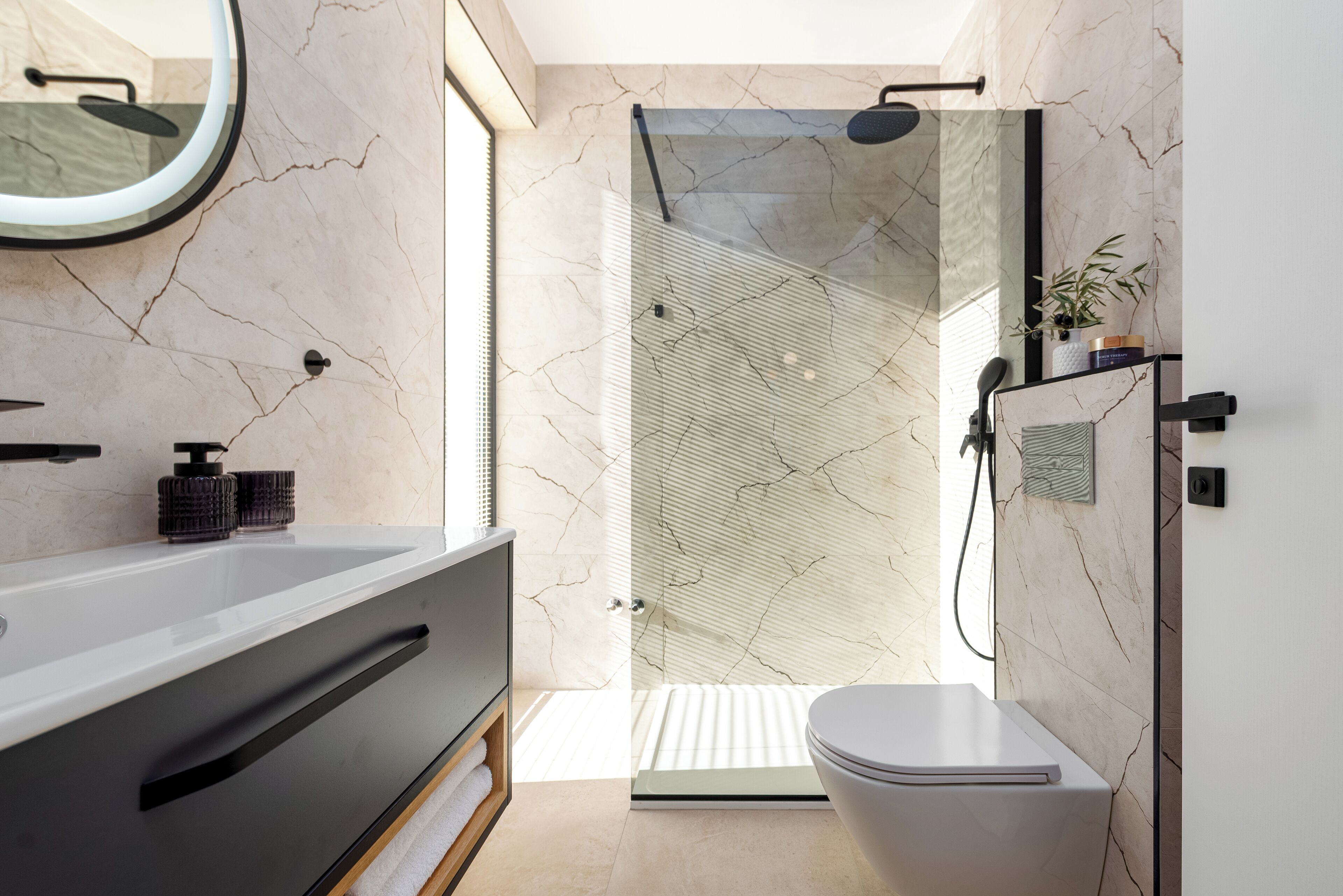 Une salle de bain moderne avec un grand miroir, une baignoire, des toilettes et une douche séparée par une paroi en verre.