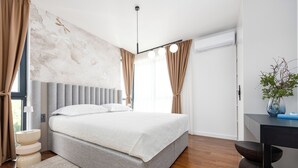 Une chambre à coucher moderne avec un grand lit, une table de chevet, un bureau et une plante en pot.