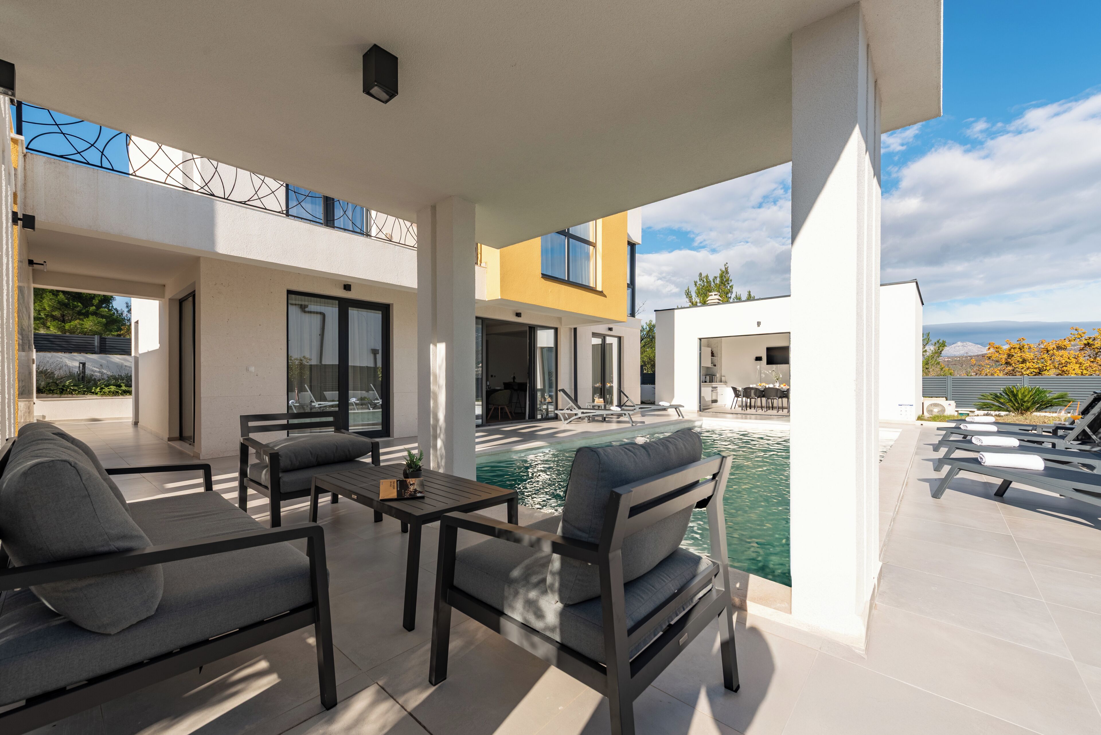 A modern outdoor pool area with lounge chairs, a table, and a seating arrangement.