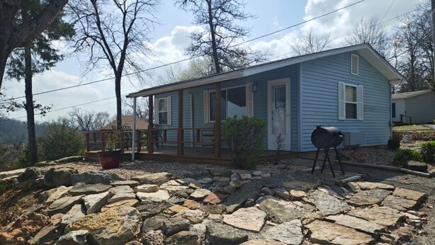 A house with a stone patio, a barbecue grill, and a covered porch. - Open Lakeview Cottage #5 at Teal Point Resort on Lake Norfork (Mountain Home)