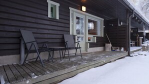 A wooden cabin with a porch, two benches, and a window with shutters. - Villa rokua by Interhome (Utajärvi)