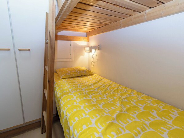 A small, single-bed room with a wooden ceiling and white walls.