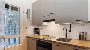 A modern kitchen with a window, a coffee maker, a sink, and cabinets. - Villa rokua by Interhome (Utajärvi)