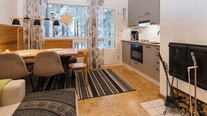 A modern kitchen with a wooden ceiling, a dining area with a table and chairs, and a fireplace. - Villa rokua by Interhome (Utajärvi)
