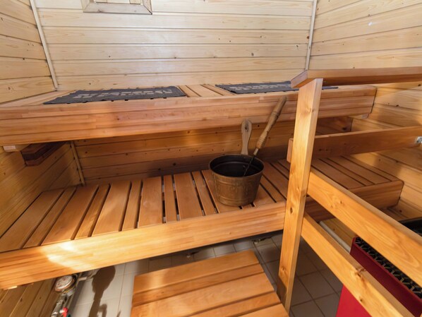 A sauna with wooden benches and a central heating element.