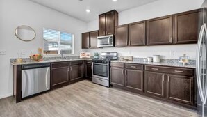 A modern kitchen with dark wood cabinets, stainless steel appliances, and a granite countertop.