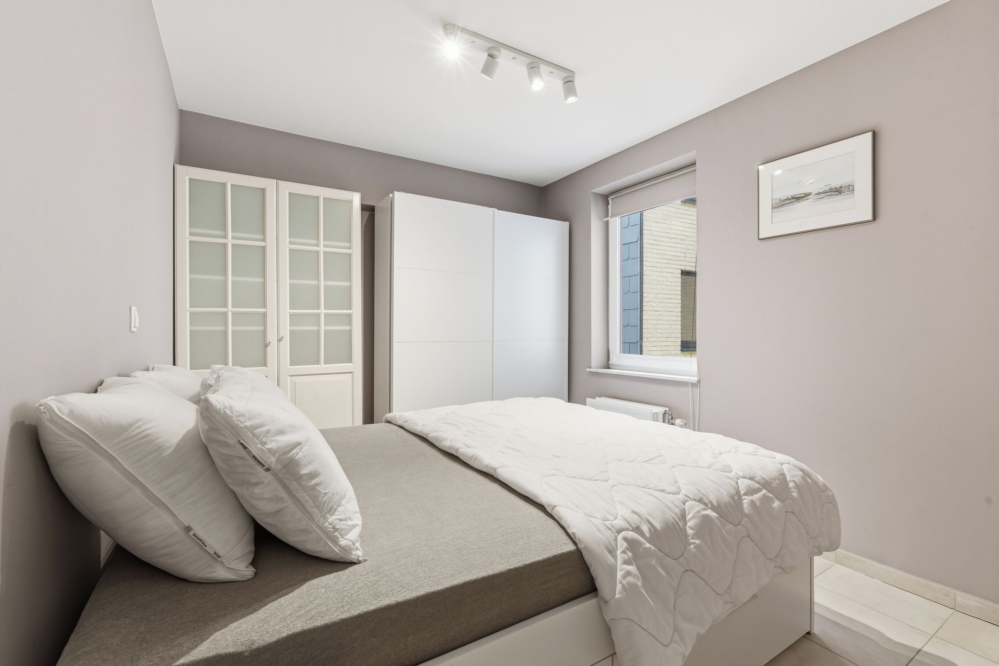 Ein Schlafzimmer mit einem Bett, einem weißen Kleiderschrank und einem Fenster.