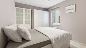 A bedroom with a bed, white wardrobe, and a window. - Walter Vilain 0301 + G* (Sint Idesbald)