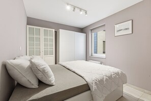 A bedroom with a bed, white wardrobe, and a window. - Walter Vilain 0301 + G* (Sint Idesbald)