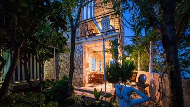 Uma casa de pedra com pátio, área de estar ao ar livre e uma estátua.