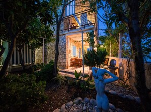 Une maison en pierre dotée d’un patio, d’un espace salon extérieur et d’une statue.
