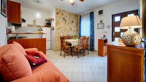 Um espaço compacto com cozinha americana, área de refeições e sala de estar com sofá e cadeiras.