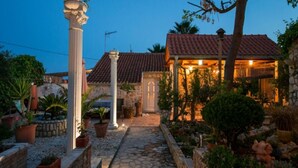 A stone pathway leading to a building with a tiled roof and a covered outdoor area. - Golden Coast Apartments - A2 - OneBedroom Apartment with Terrace and SeaView (Vis)