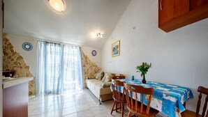 A dining area with a table covered in a blue tablecloth, wooden chairs, and a vase with flowers. - Golden Coast Apartments - A2 - OneBedroom Apartment with Terrace and SeaView (Vis)