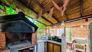 A rustic kitchen with a brick oven, a small refrigerator, and a stone-tiled floor. - Golden Coast Apartments - A2 - OneBedroom Apartment with Terrace and SeaView (Vis)