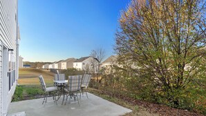 A patio with a table and chairs, a tree, and a row of houses in the background. - Cozy Garden-Level Retreat 3 Queen Beds (Raleigh)