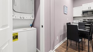 A laundry area with a washing machine and dryer, a microwave, and a dining table with chairs. - Cozy Garden-Level Retreat 3 Queen Beds (Raleigh)
