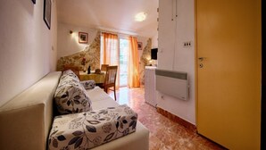 Ein gemütliches Wohnzimmer mit Sofa, Essbereich mit Tisch und Stühlen, einer Steinwand und einer Tür.