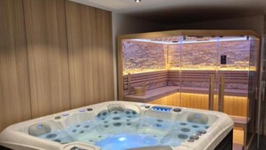 Um spa moderno com banheira de hidromassagem e área de massagem separada por vidro.