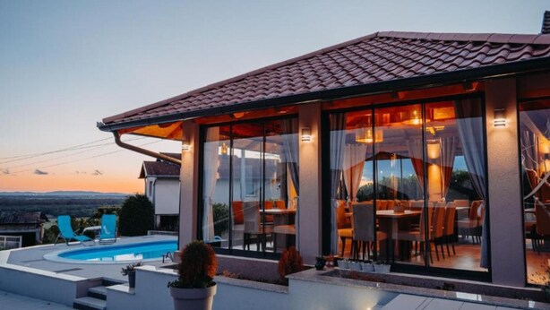 Uma casa moderna com piscina, área de estar externa e grandes janelas.