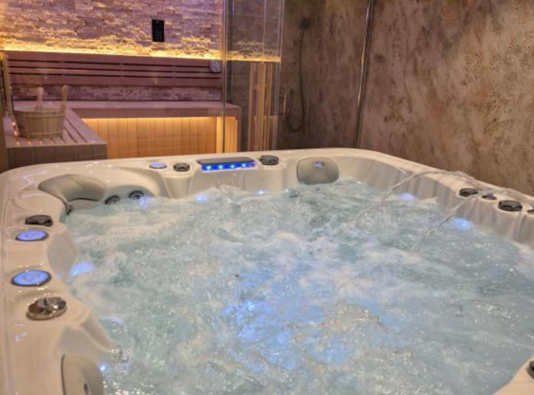 A hot tub with multiple control buttons and a wooden bench in the background.