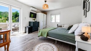 Un dormitorio con cama, escritorio, silla, televisor y ventana.