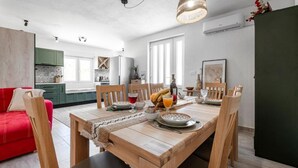 Una cocina moderna con muebles de madera, una mesa de comedor dispuesta con platos y vasos, y un sofá rojo en la zona de estar.