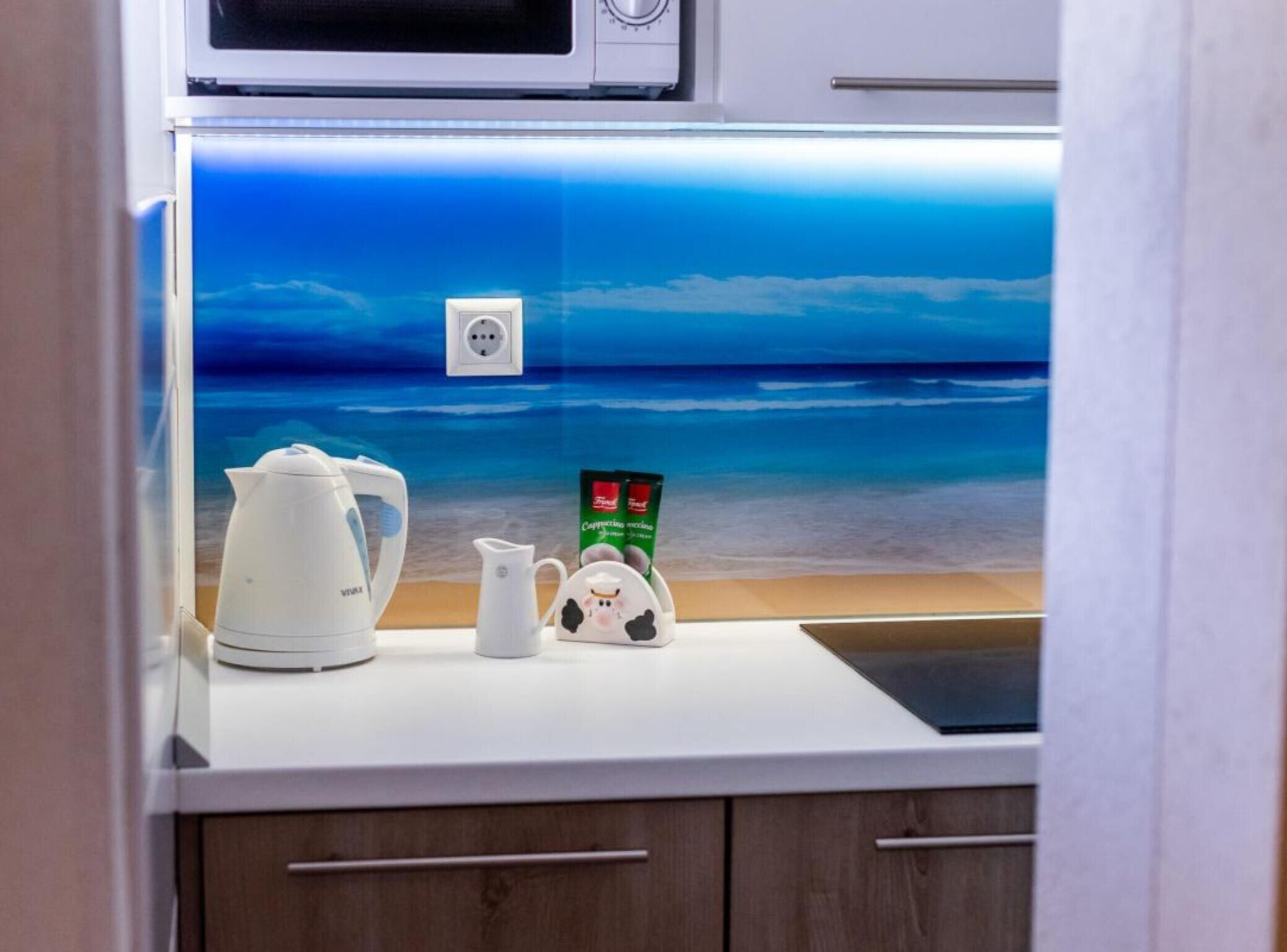 Una encimera de cocina con una cafetera, una jarra de leche y un sobre de crema para café.