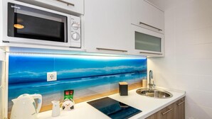 Una cocina con microondas, un lavamanos y un salpicadero decorativo.