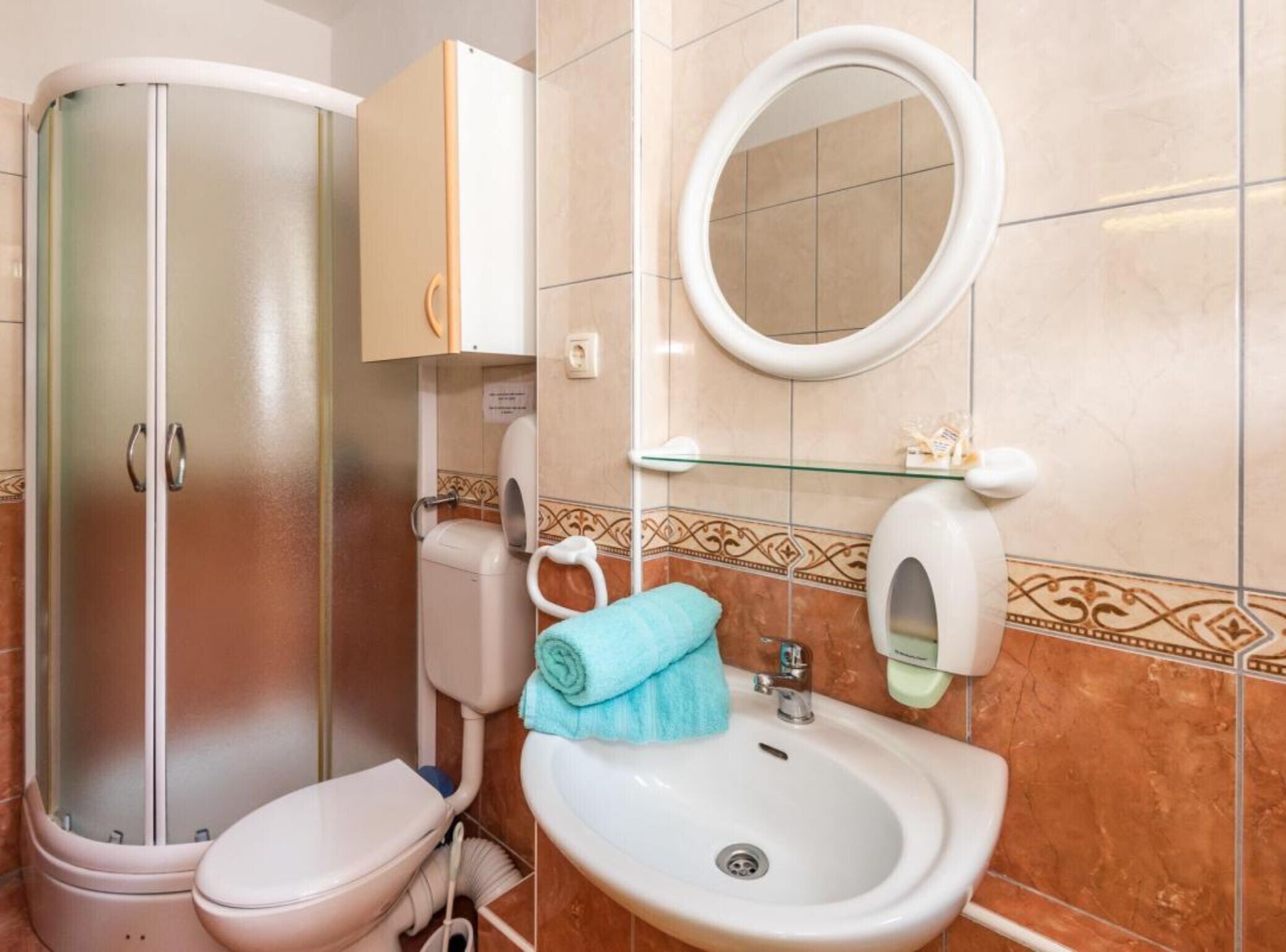 A bathroom with a glass-enclosed shower, a toilet, a sink, and a mirror.