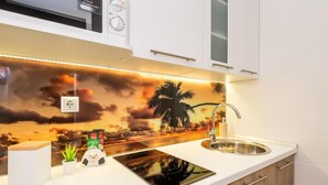 A kitchen with a modern design, featuring a built-in stove, a sink, and wooden cabinets. - Villa Goldfield - One Bedroom Apartment with Balcony (Gradac)